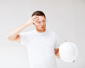 Image showing male architect in safety glasses taking off helmet