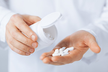 Image showing doctor hands holding white pack and pills