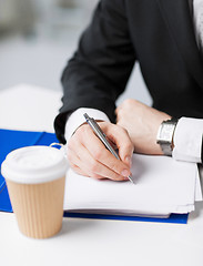 Image showing businessman with coffee writing something