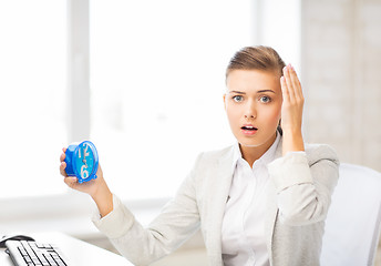 Image showing stressed businesswoman holding clock