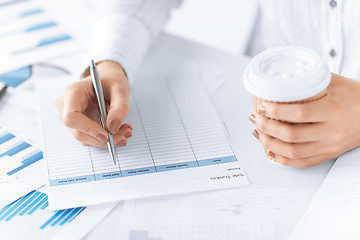 Image showing woman filling in form and drinking coffee