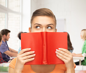 Image showing woman eyes and hands holding red book