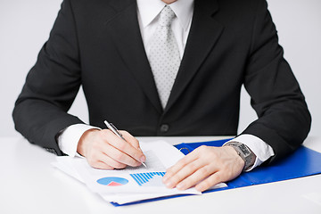 Image showing businessman working and signing papers
