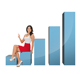 Image showing beautiful businesswoman sitting on big 3d chart