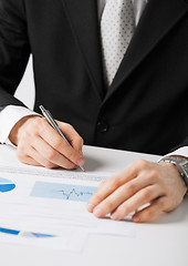 Image showing businessman working and signing paper