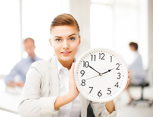Image showing businesswoman showing white clock in office