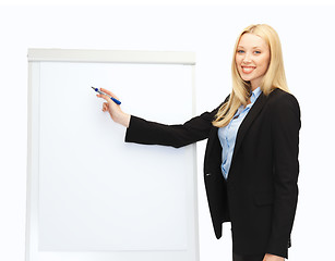 Image showing businesswoman writing on flipchart in office