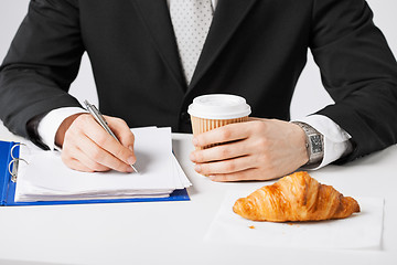 Image showing businessman with coffee writing something