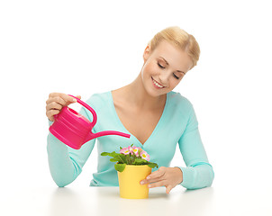 Image showing housewife with flower in pot and watering can