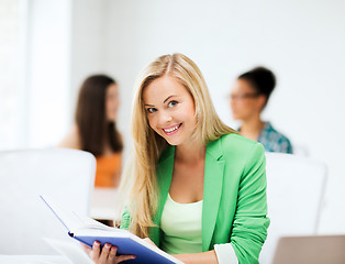 Image showing smiling student girl reading book at school