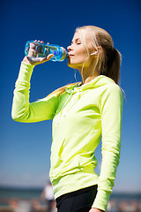 Image showing woman drinking water after doing sports outdoors