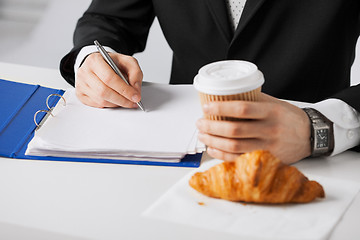 Image showing businessman with coffee writing something