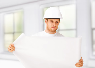 Image showing male architect looking at blueprint at home