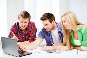 Image showing smiling students looking at laptop at school