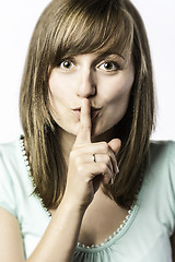 Image showing Young woman holds a finger to her mouth