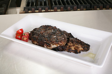 Image showing Rib-eye steak resting on the plate in the kitchen ready to serve