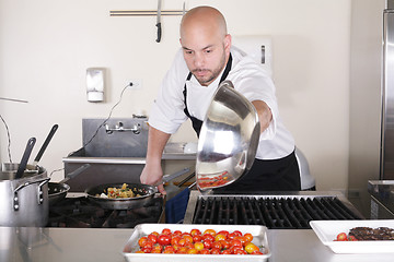 Image showing Chef in kitchen cooking, he is working on the sauce for the food