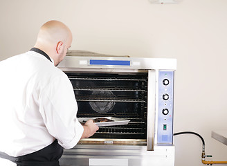 Image showing chef putting a tray of a juicy steak in a professional oven