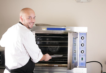 Image showing Happy young chef cooking steak in the oven 