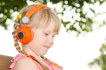 Image showing Girl sitting on bench in park and listening language audio cours