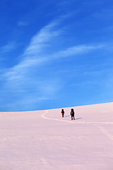 Image showing Two hikers on sunrise snow plateau