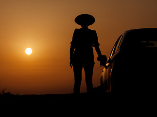 Image showing Silhouette woman with hat standing near car