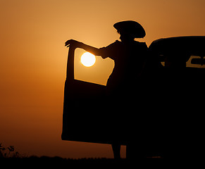 Image showing Silhouette woman with hat standing near car