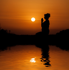 Image showing Silhouette woman sitting and relaxing against orange sunset