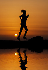 Image showing Silhouette woman running against orange sunset