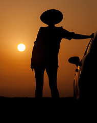 Image showing Silhouette woman with hat standing near car