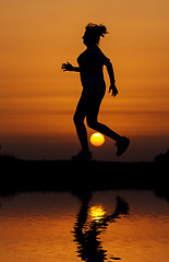 Image showing Silhouette woman running against orange sunset