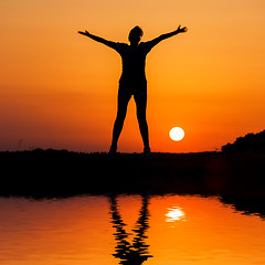 Image showing Silhouette woman jumping against orange sunset