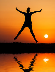 Image showing Silhouette woman jumping against orange sunset