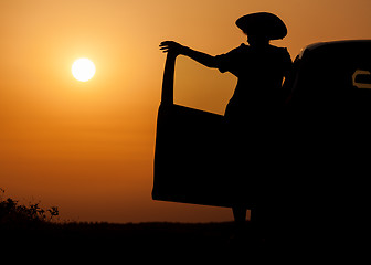 Image showing Silhouette woman with hat standing near car