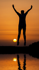 Image showing Silhouette woman jumping against orange sunset