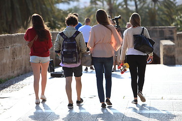 Image showing Rear view of four students walking away
