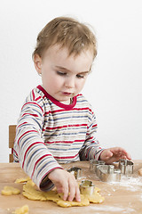 Image showing child working with dough on wooden desk