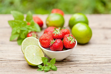 Image showing fresh tasty sweet strawberries and green lime outdoor in summer