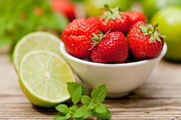 Image showing fresh tasty sweet strawberries and green lime outdoor in summer