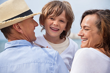 Image showing happy family sitting on rock and watching the ocean waves