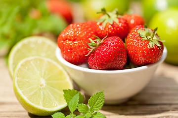 Image showing fresh tasty sweet strawberries and green lime outdoor in summer