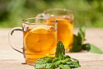Image showing fresh tasty hot tea lemon and mint outdoor in summer 