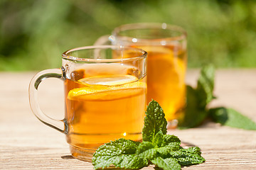 Image showing fresh tasty hot tea lemon and mint outdoor in summer 