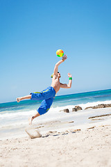 Image showing attractive young man playing volleyball on the beach