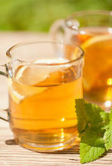 Image showing fresh tasty hot tea lemon and mint outdoor in summer 