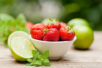 Image showing fresh tasty sweet strawberries and green lime outdoor in summer