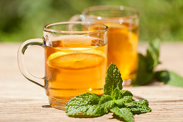 Image showing fresh tasty hot tea lemon and mint outdoor in summer 