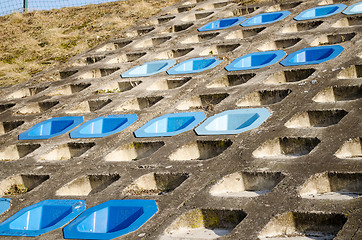 Image showing cement slope surface mounted four row blue chairs 