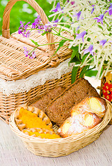 Image showing Buns in a wicker basket and a bouquet of field flowers  close-up