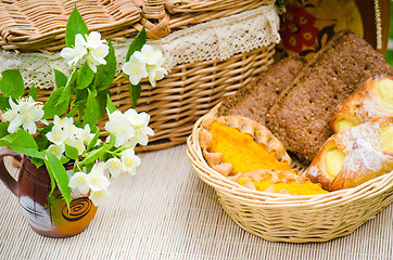 Image showing Buns in a wicker basket and a bouquet of jasmine flowers  